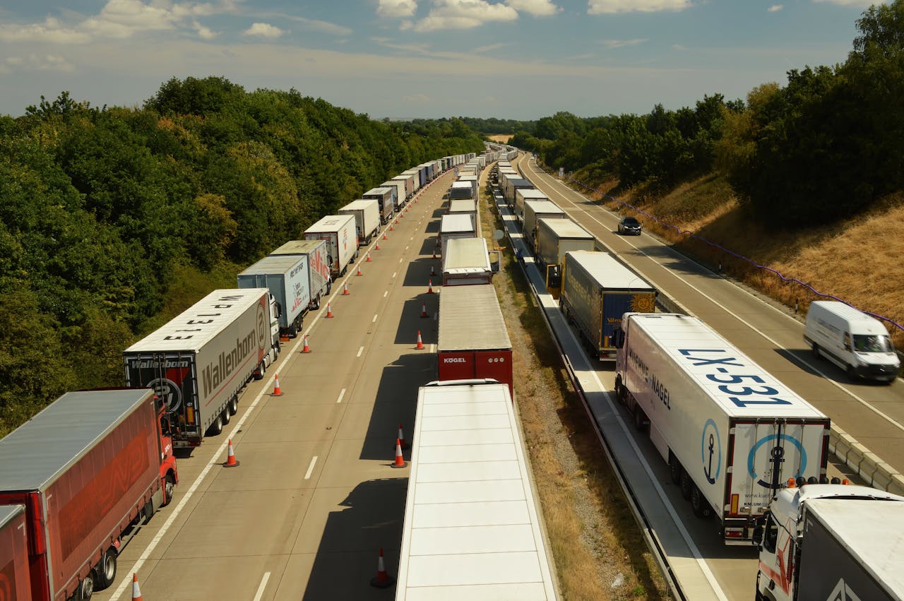 A high-angle shot of trucks and trailers in traffic on a highway in England beneath a bright sky.