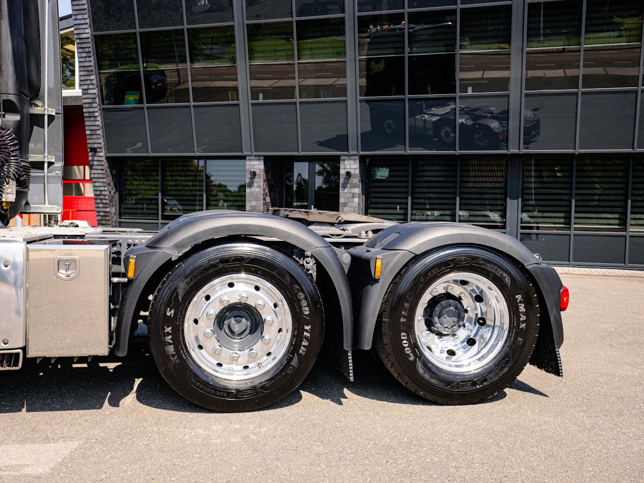 Detail of truck wheels with reflective building backdrop in Andijk, Netherlands.